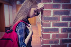 Worried student leaning against the wall at the university