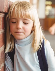 Sad pupil being bullied by classmates at corridor in school