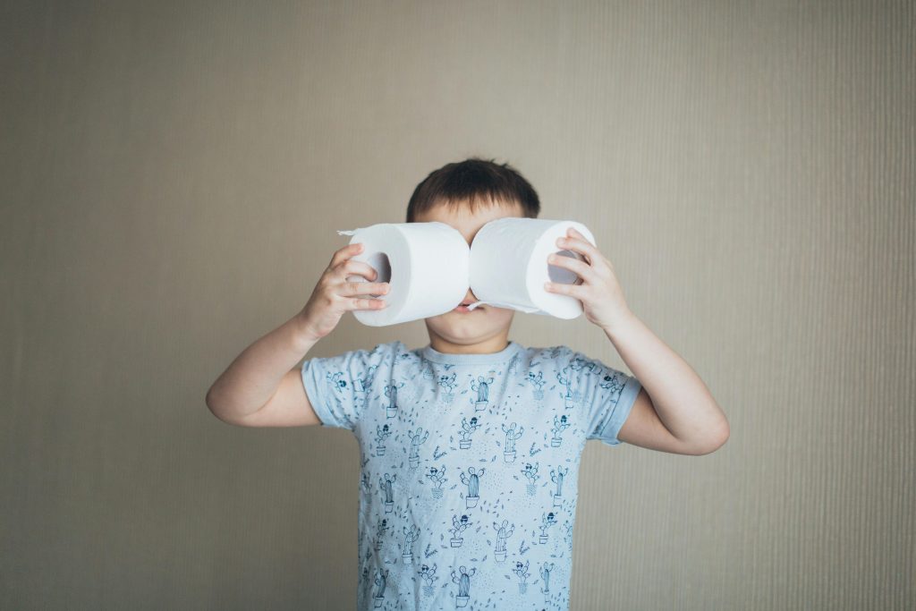 Young boy hiding behind toilet rolls